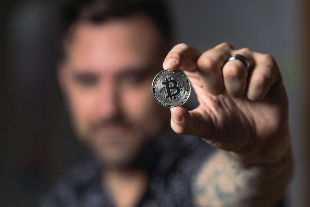 pexels-photo-1447418-1447418 Adult male hand holding a Bitcoin, showcasing cryptocurrency focus indoors.